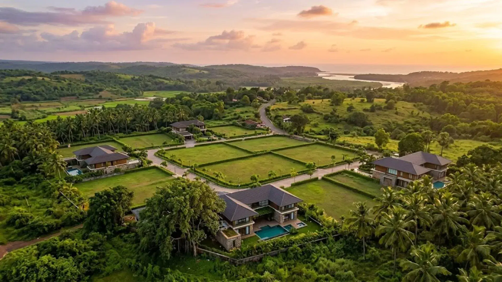Aerial view of plotted land and luxury villas surrounded by greenery in Goa at sunset