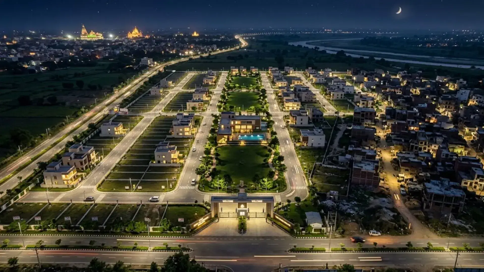 Aerial view of a planned plotted development in Vrindavan with internal roads, residential plots and surrounding city infrastructure at night